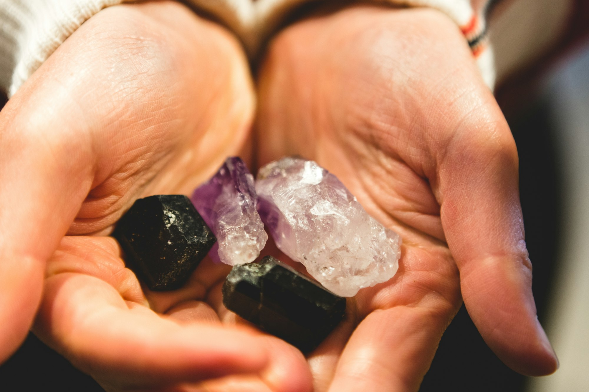 Hands holding beautiful gemstones and crystals, quartz of different colors