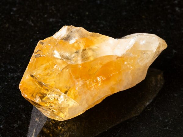 raw crystal of Citrine gemstone on black